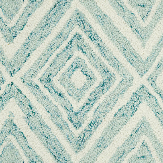 Wool broadloom carpet swatch in a painterly diamond pattern in cream and blue speckled with turquoise.