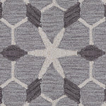 Wool broadloom carpet swatch in a geometric lattice pattern in cream and charcoal on a gray field.