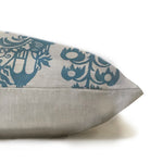 Side view of a throw pillow in tan. One side is solid and the other has a repeating block print in navy.