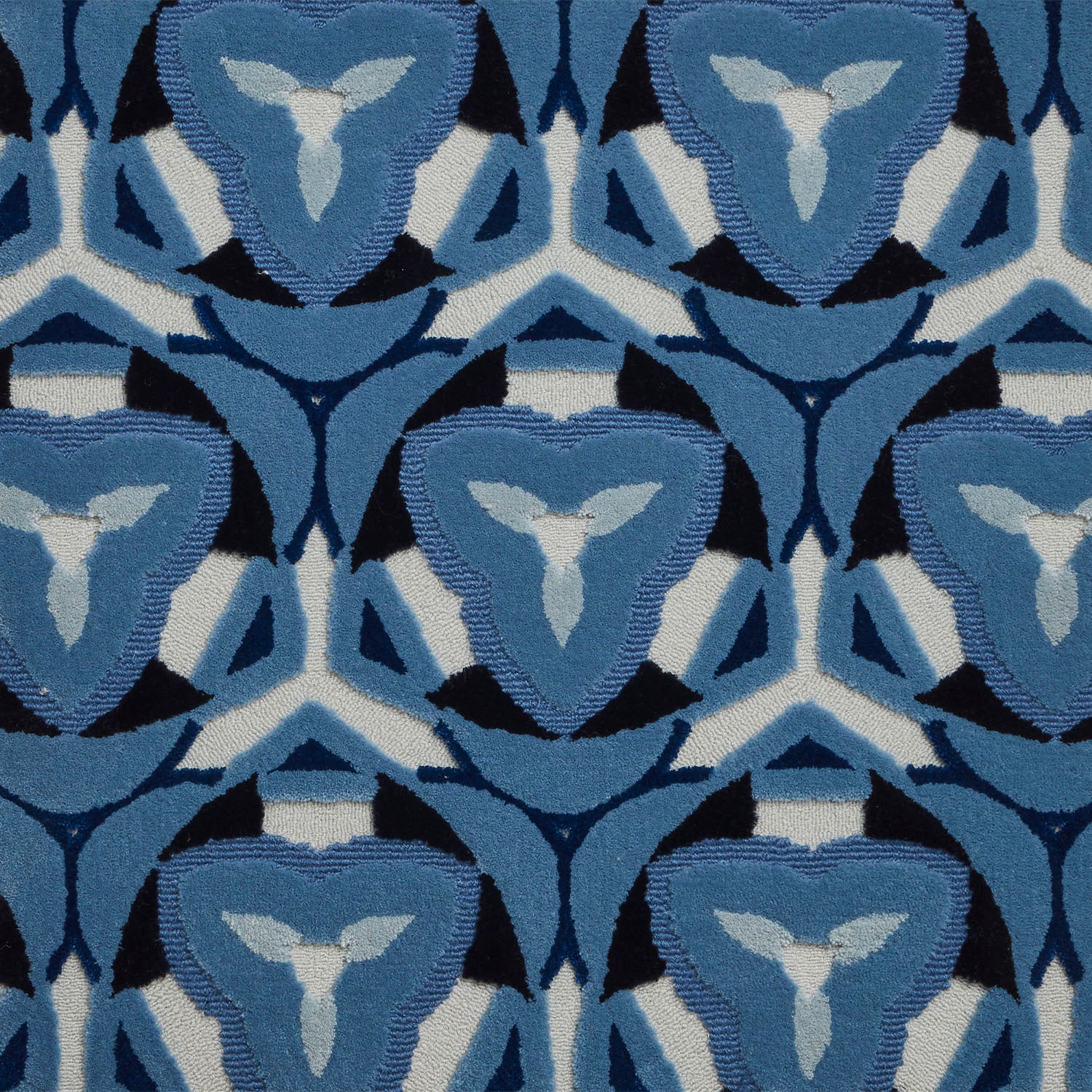 Detail of Gigi Rug featuring a geometric floral motif with a mix of cut pile and linear loops in ivory and shades of blue