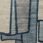 Woven rug swatch in a large-scale abstract pattern of overlapping square shapes in shades of navy, tan and brown.