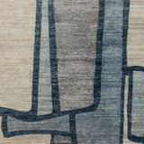 Woven rug swatch in a large-scale abstract pattern of overlapping square shapes in shades of navy, tan and brown.