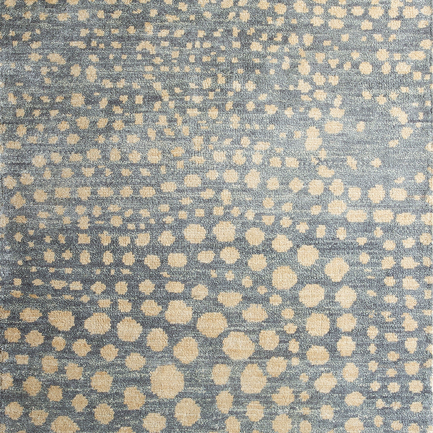Woven rug swatch in a pattern of many repeating different-sized circles in tan on a blue-gray field.
