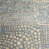 Woven rug swatch in a pattern of many repeating different-sized circles in tan on a blue-gray field.