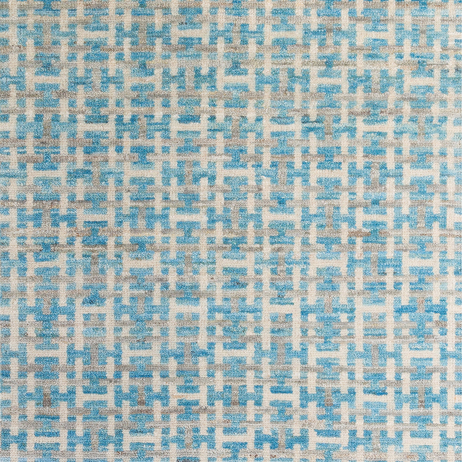 Woven rug swatch with an interlocking linear "gate" pattern in shades of white and gray on a sky-blue field.