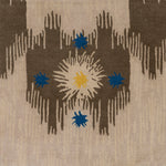 Detail of Estrella Rug in Quarry features a painterly abstract ikat in brown and taupe with star shaped accents in blue and yellow