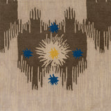 Detail of Estrella Rug in Quarry features a painterly abstract ikat in brown and taupe with star shaped accents in blue and yellow
