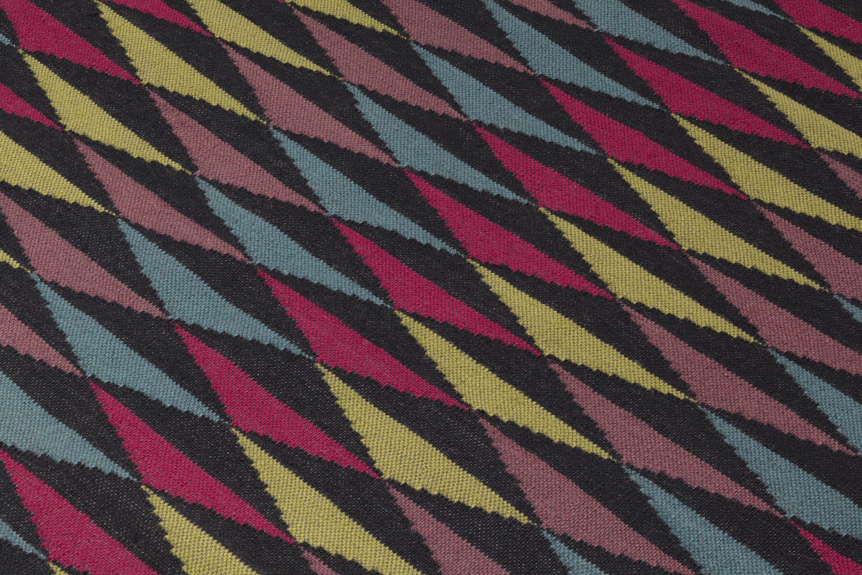Detail of the Trio Rug in Jewel, a stacked triangle pattern with black, ruby red, blue, heather purple and yellow. 