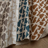 Cascade of folded Vessels swatches in Stone, Plaster, Petrol and Tobacco on top of a wooden floor. 