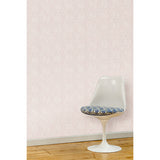 A white swivel chair in front of a wall papered in a large-scale repeating leaf print in white on a light pink watercolor background.