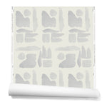 Partially unrolled wallpaper in a large-scale pattern of abstract gray watercolor shapes on a cream background.