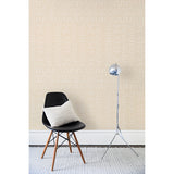 A chair and floor lamp in front of a wall papered in a minimalist African-inspired line design of painted white on a beige background.