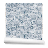 Partially unrolled wallpaper in a dense hand-drawn geometric motif in shades of navy on a white background.