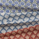 A row of three folded fabrics, each with a repeating Moroccan-inspired scallop pattern, each in a different green, red or bue colorway.